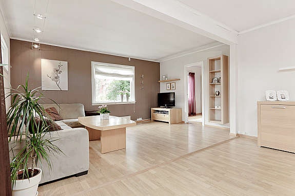 Romslig og flott stue med ildsted. Malte flater og laminat på gulv. Galleribilde