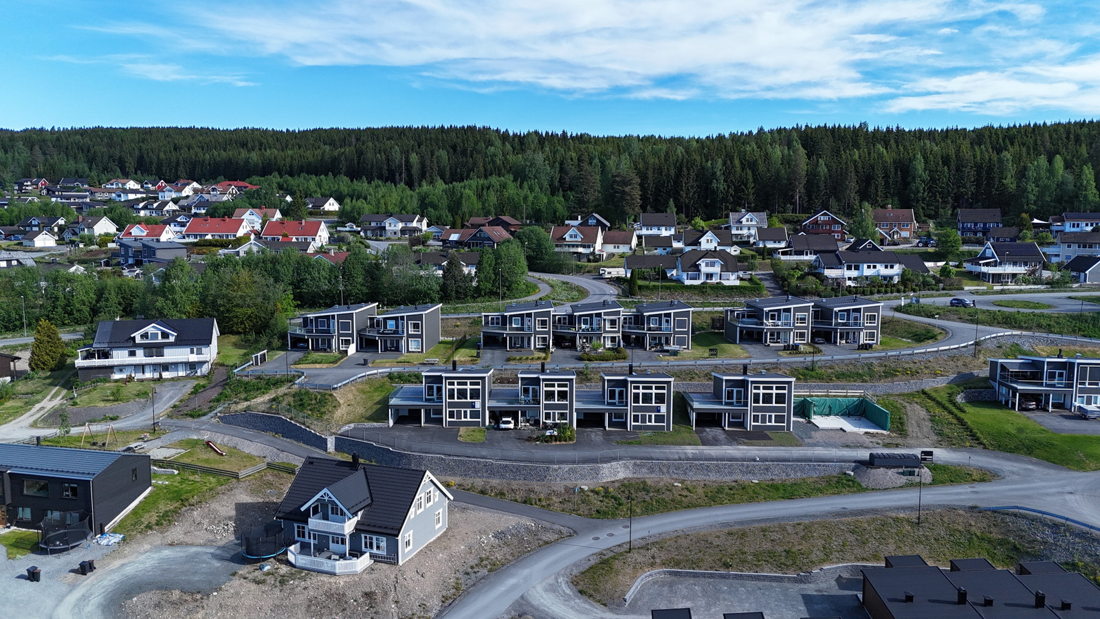 Boligen ligger helt til venstre i rekken bak eneboligen på bildet.