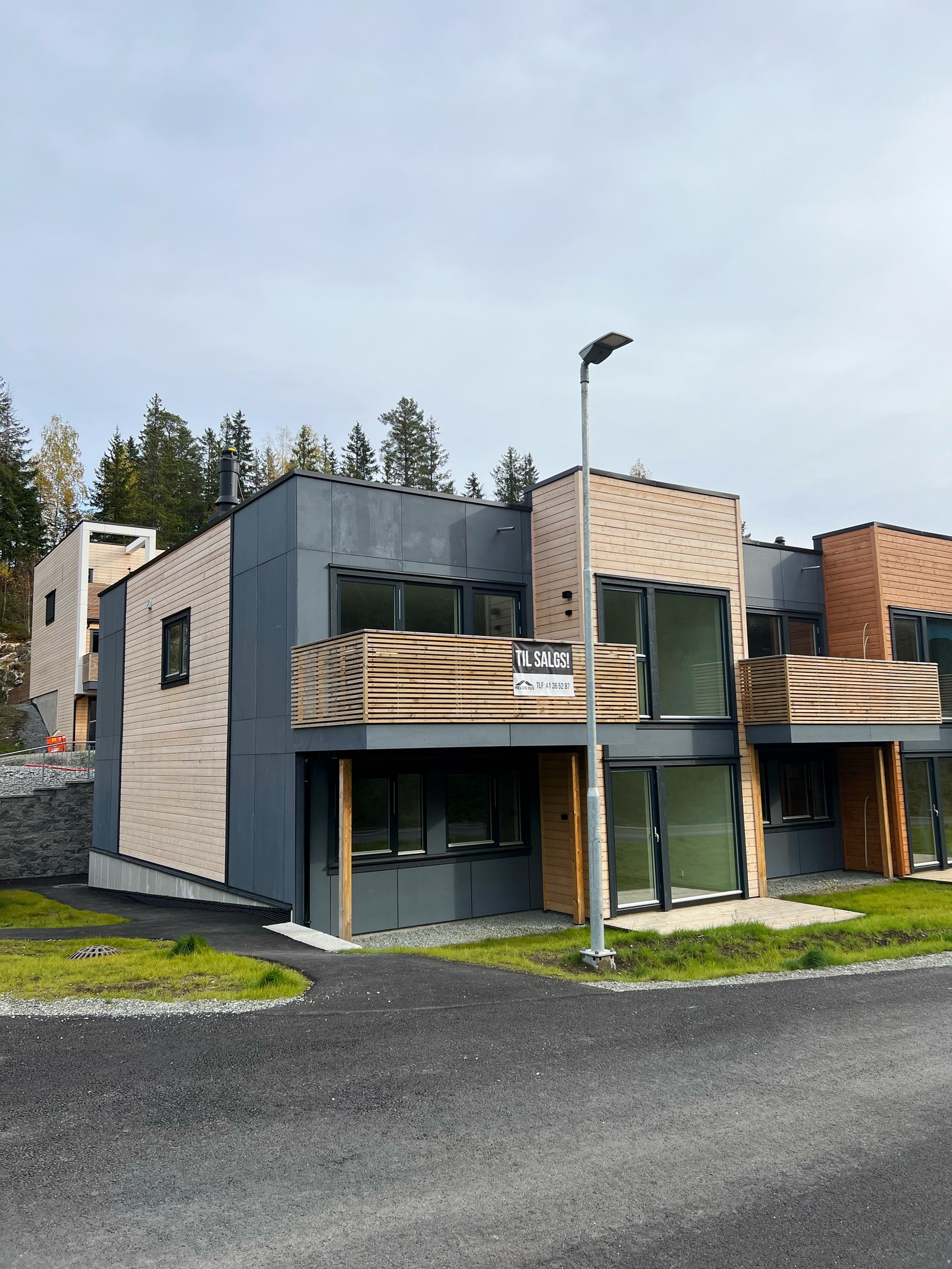 Hovedfasade med vestvendt balkong og uteplass på terreng