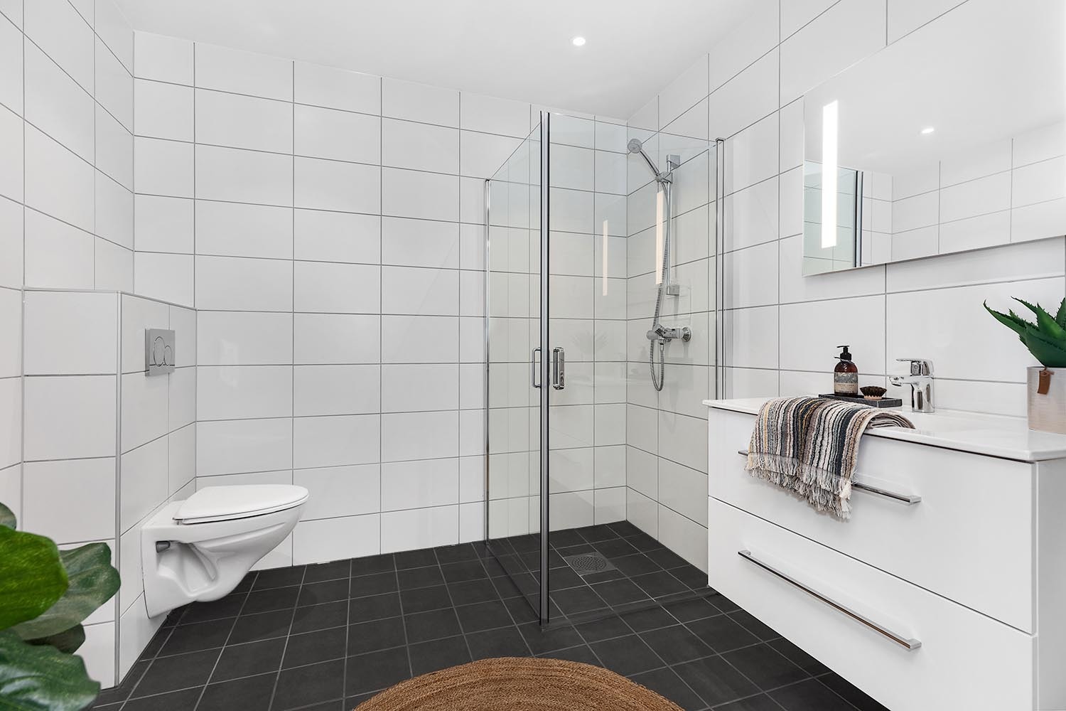 Gode og romslige bad med nøytrale og fine fliser på gulv og vegg.