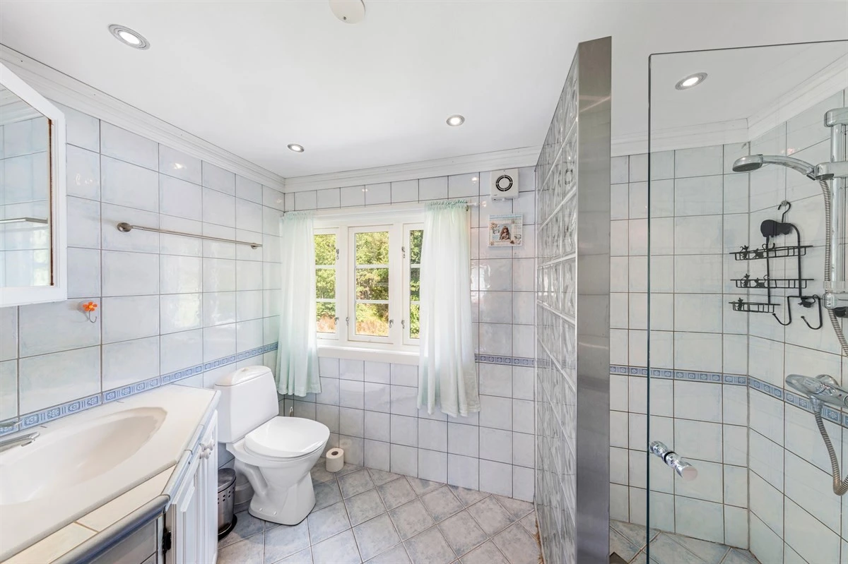 Flislagt bad med baderomsinnredning og servant, gulvmontert toalett og dusjnisje. Galleribilde