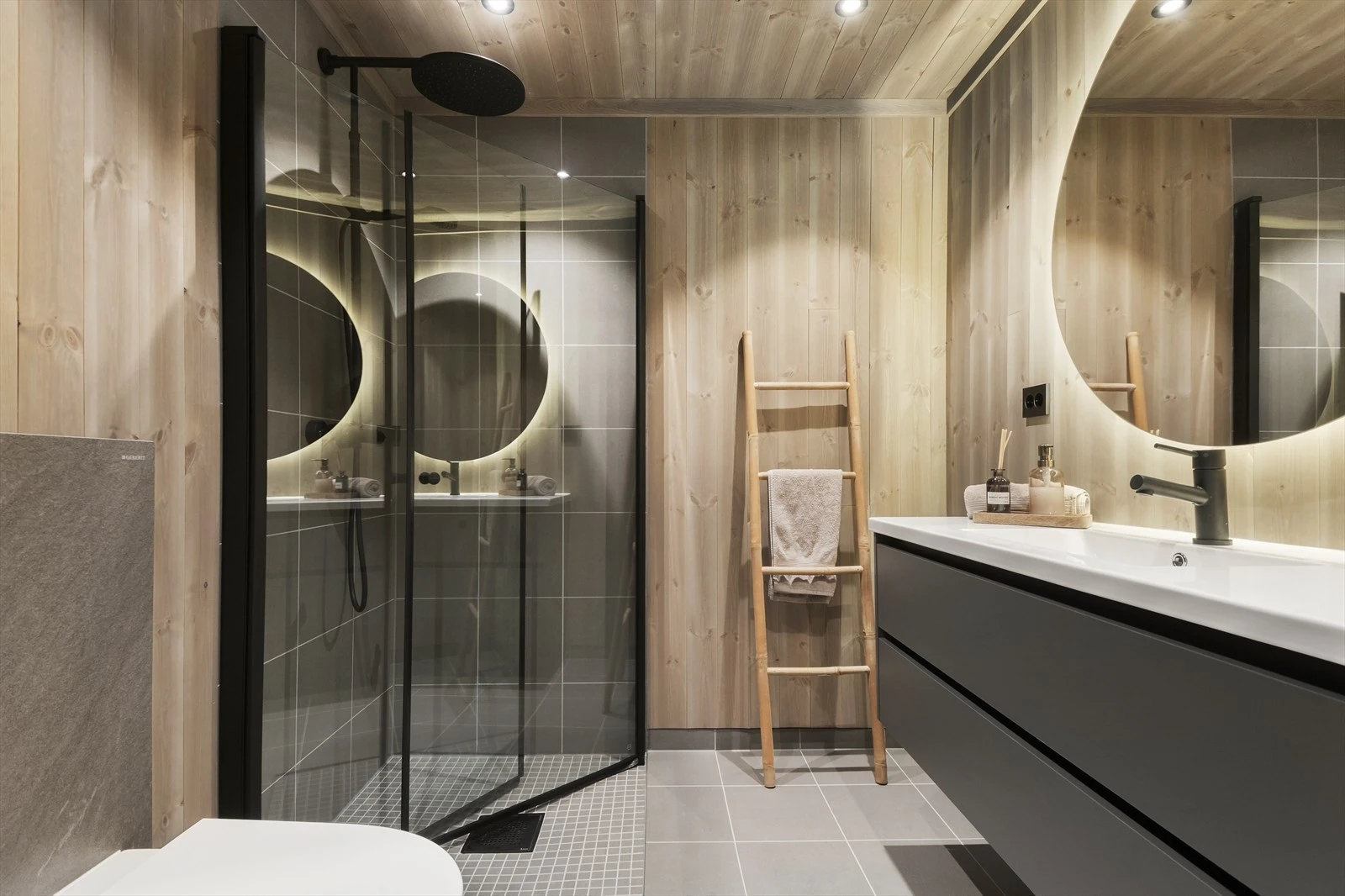 Baderom med fliser på gulv og fabrikkbeiset glatt furupanel på vegger og i himling. Fliser i dusjsonen. Galleribilde