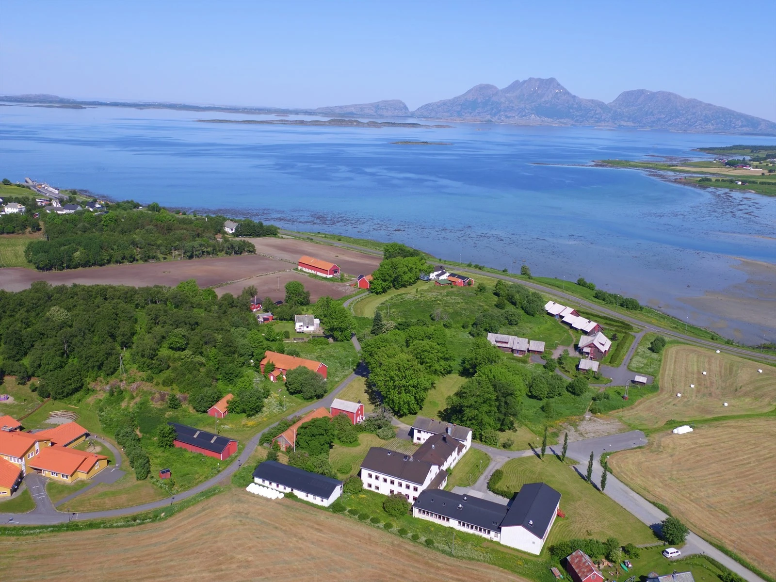 Husmorskolen med tilhørende bygg og utsikten mot Dønna og Herøy. Det som selges er bygg A, bygg B og Stabburet. Galleribilde