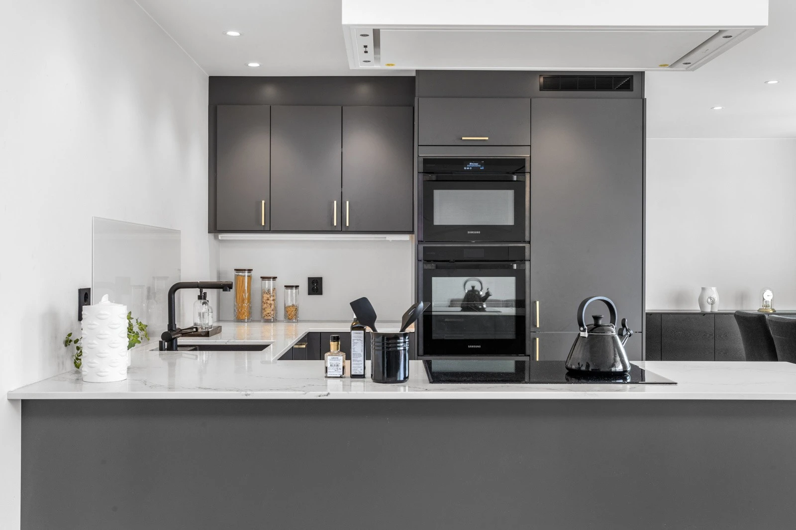 Integrert stekeovn og mikrobølgeovn i praktisk høyde, platetopp på kjøkkenøy, oppvaskmaskin og kjøleskap Galleribilde