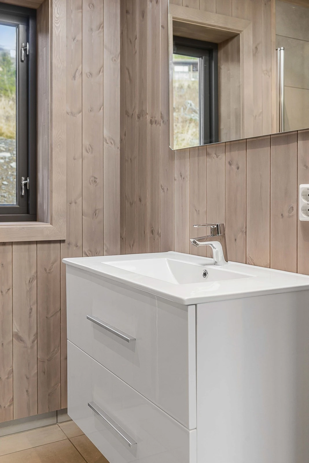 Moderne baderomsinnredning med hvite høyglans skuffefronter og heldekkende servanttopp. Galleribilde