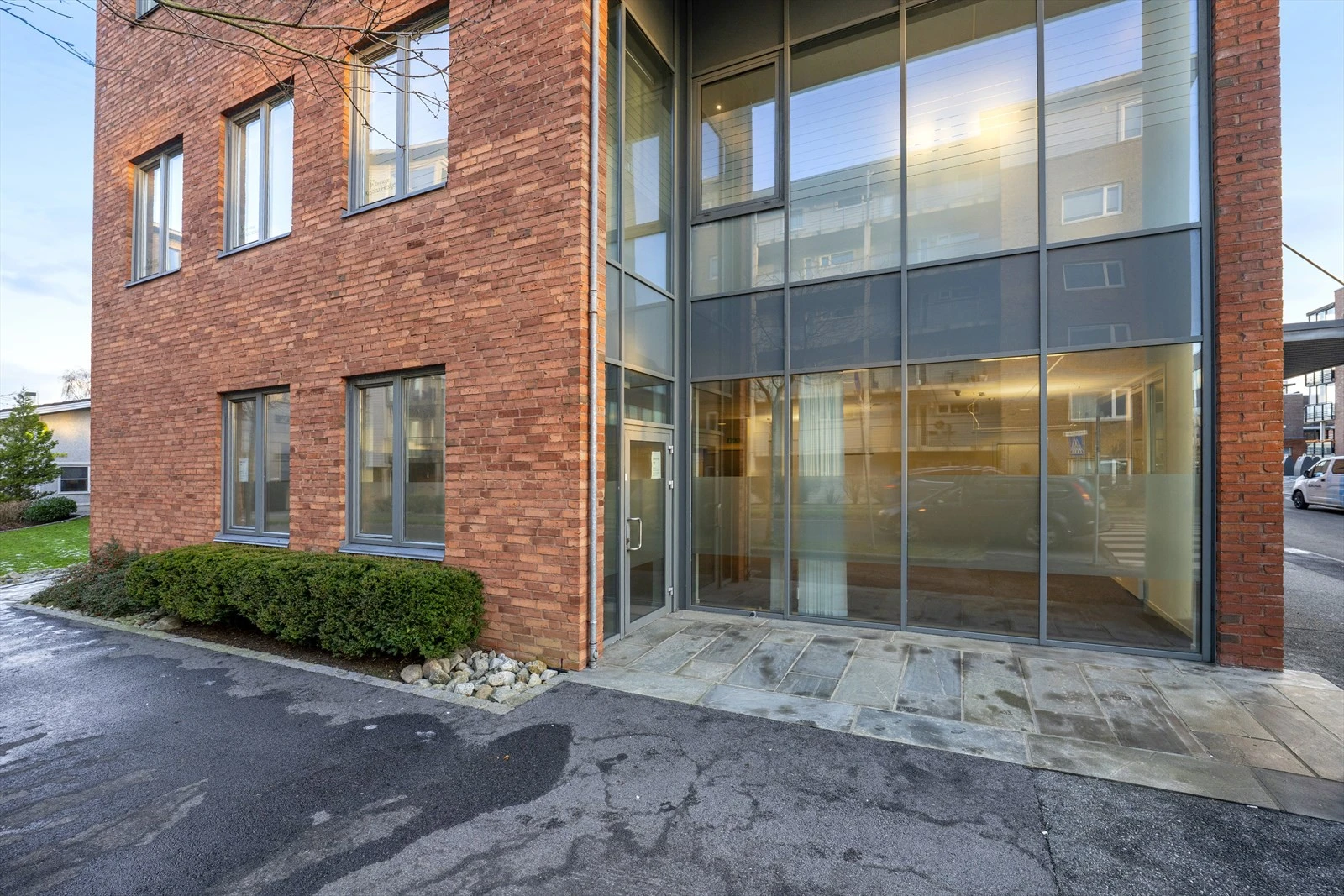 Moderne mursteinsbygning med store vinduer og inngangsparti i glass, beliggende i et attraktivt og tilgjengelig område. Galleribilde