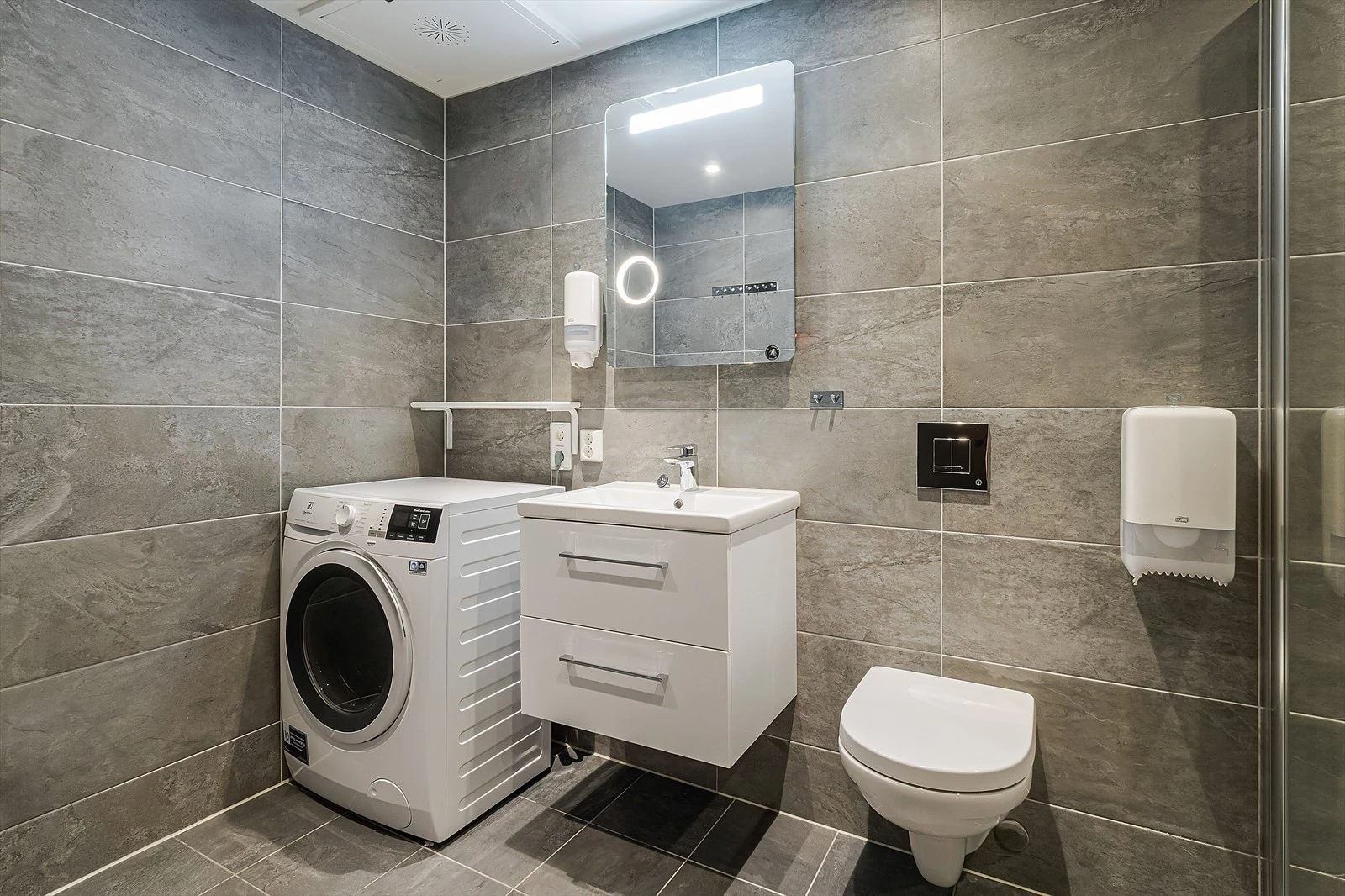 Lekkert bad innredet med dusjhjørne, toalett og servant på innredning. Galleribilde