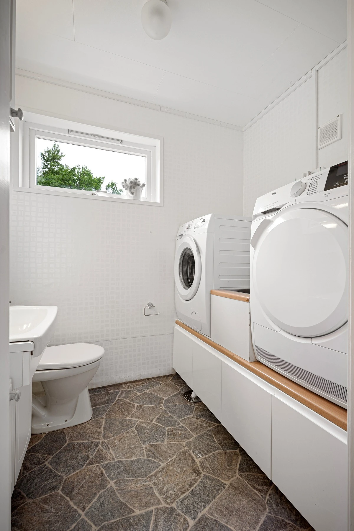 Rommet har opplegg og god plass til vaskemaskin, og det er etablert skyllekar med benkeplate mellom vaskemaskin og tørketrommel Galleribilde
