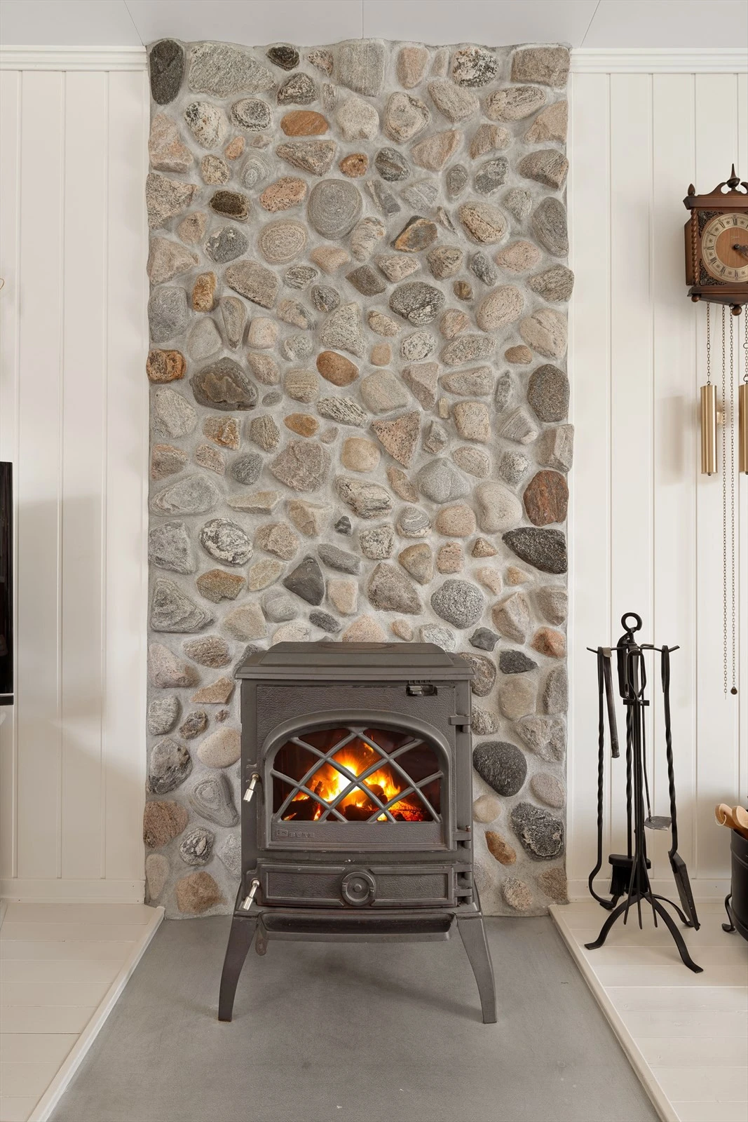 Stuen er utstyrt med vedovn som er montert foran en brannmur med naturstein. Galleribilde