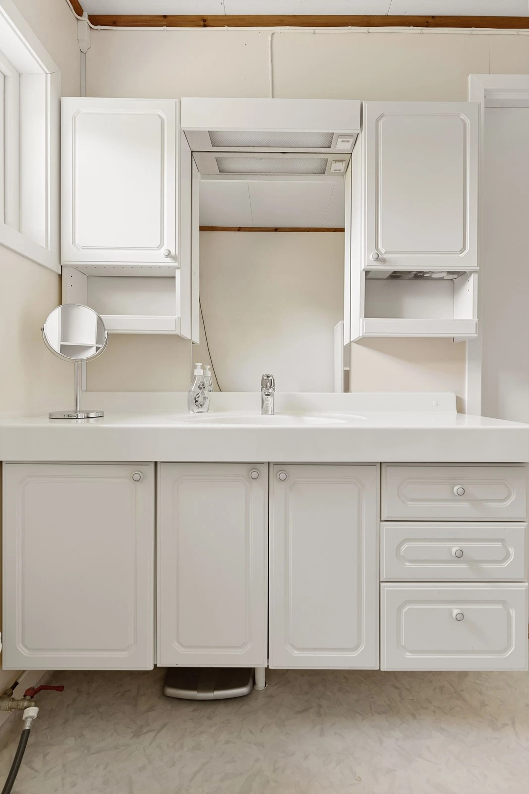 Baderomsinnredningen byr på rikelig med oppbevaringsplass bak hvite, profilerte fronter. Galleribilde