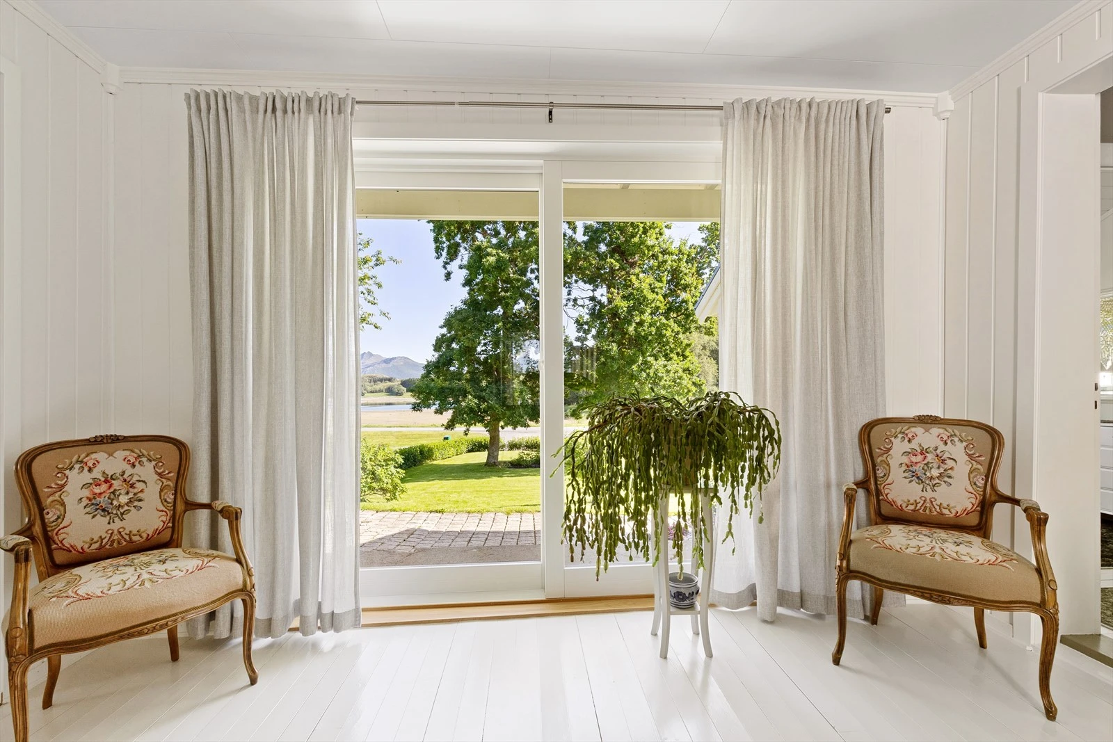 Stor, nyere skyvedør med glassfelt åpner opp til steinlagt areal utenfor stuen. Galleribilde