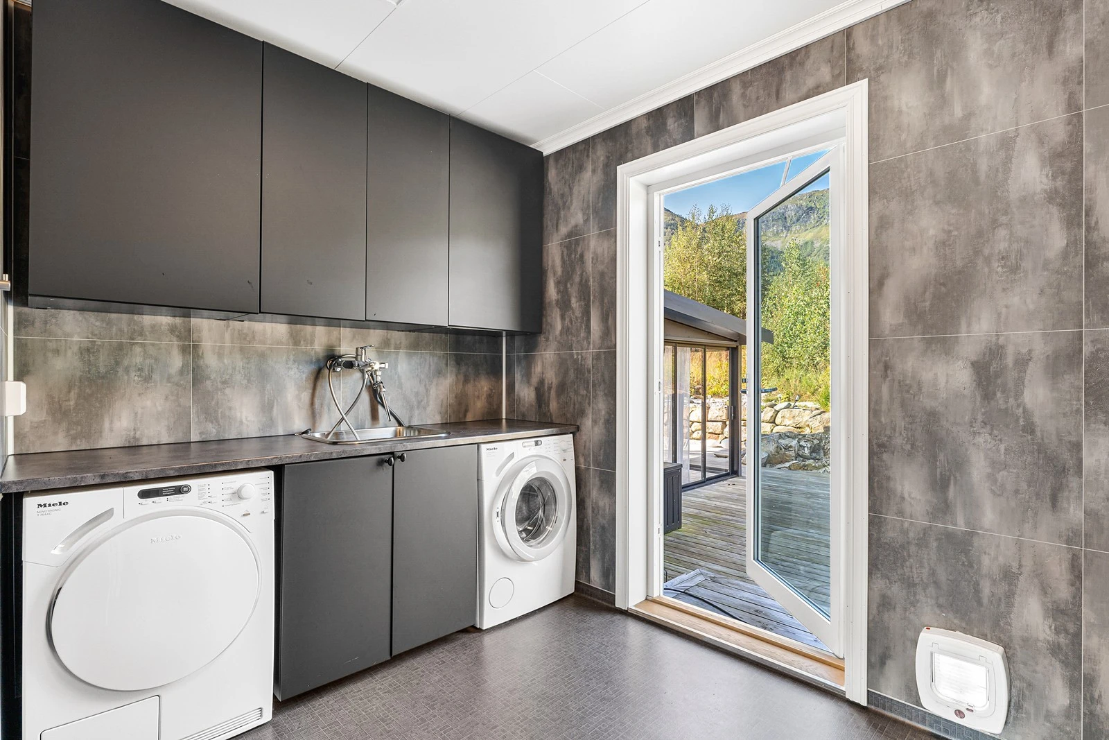 Vaskerom av god størrelse og pent innredet med vinylbelegg på gulv og baderomsplater på vegger. Galleribilde