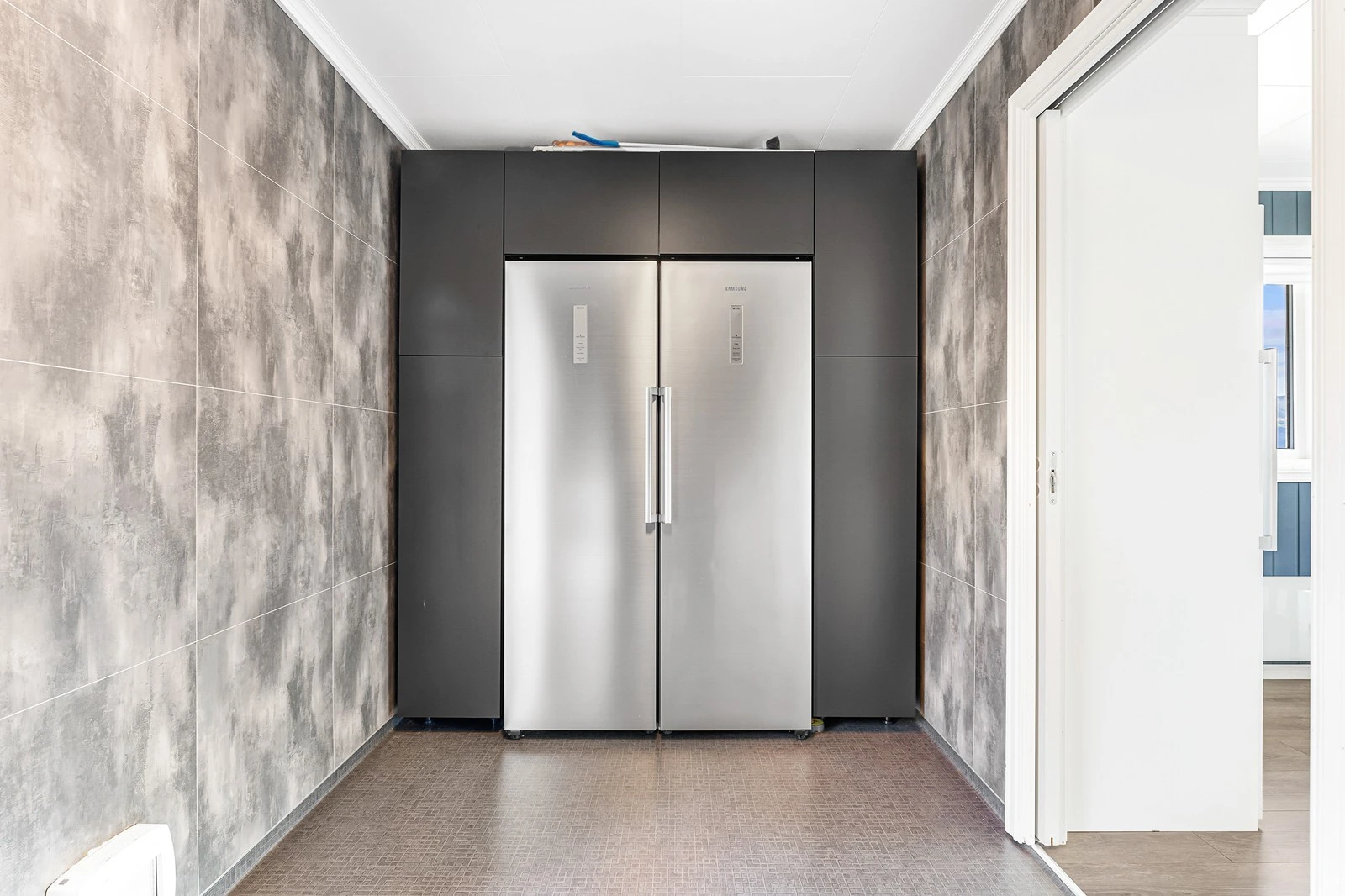 Rommet er innredet med overskap, laminert benkeplate og høyskap med side by side kombiskap. Galleribilde