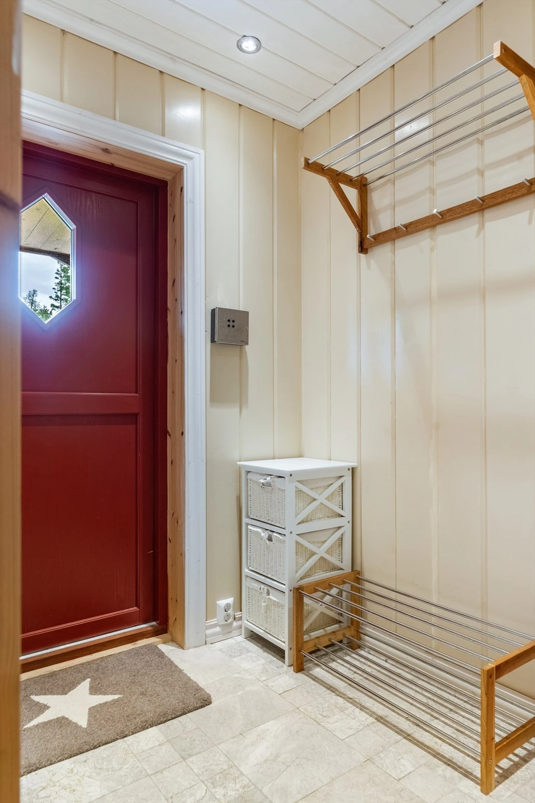 Med adkomst fra det hyggelige, overbygde inngangspartiet kommer man inn i vindfanget hvor det er fliser på gulv med varmekabler. Her er det god plass til sko samt til ytterklær på fastmontert garderobeløsning. Galleribilde