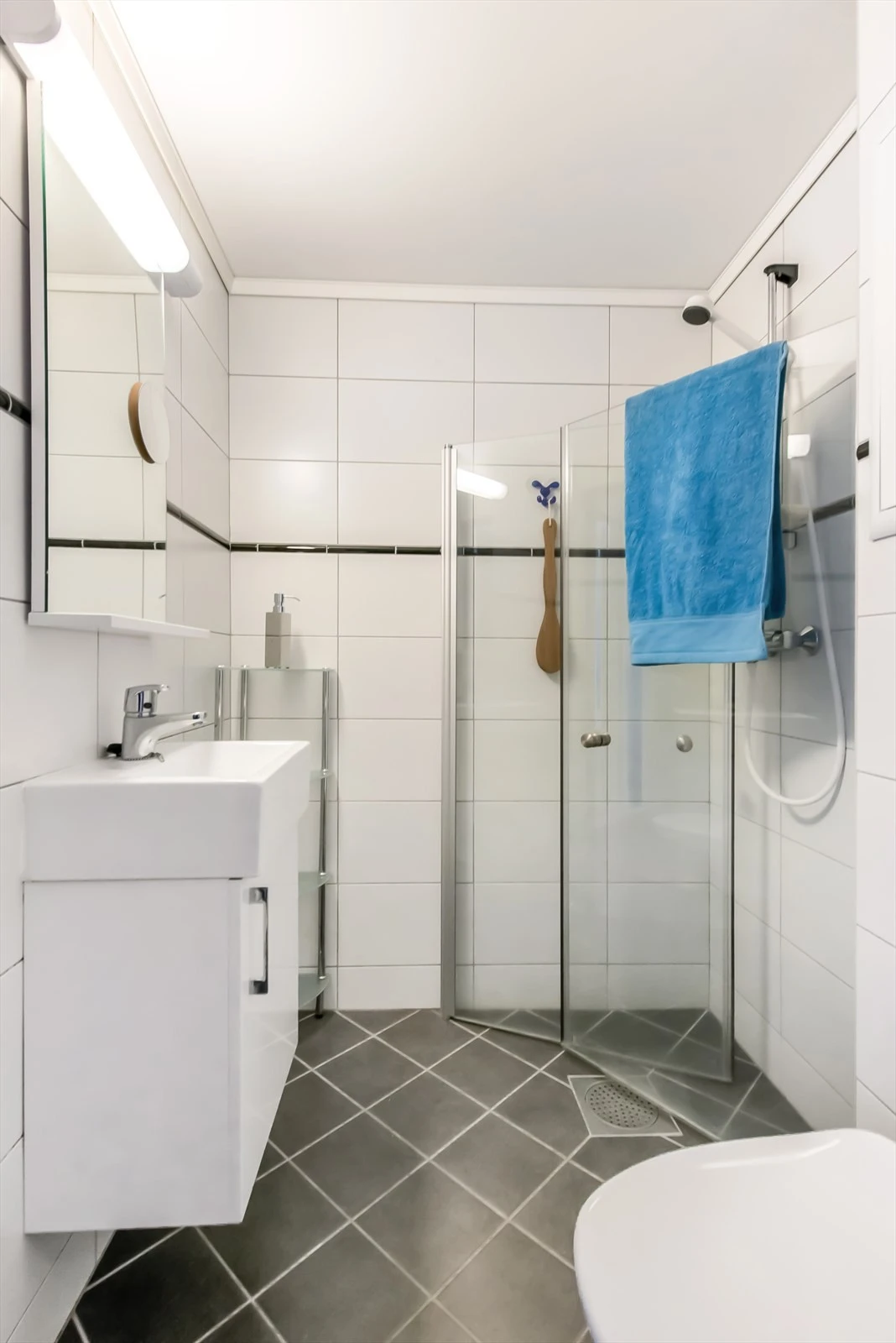 Badet er helfliset med varmekabler i gulv. Lyse, tidløse fliser og arealeffektiv innredning. Galleribilde