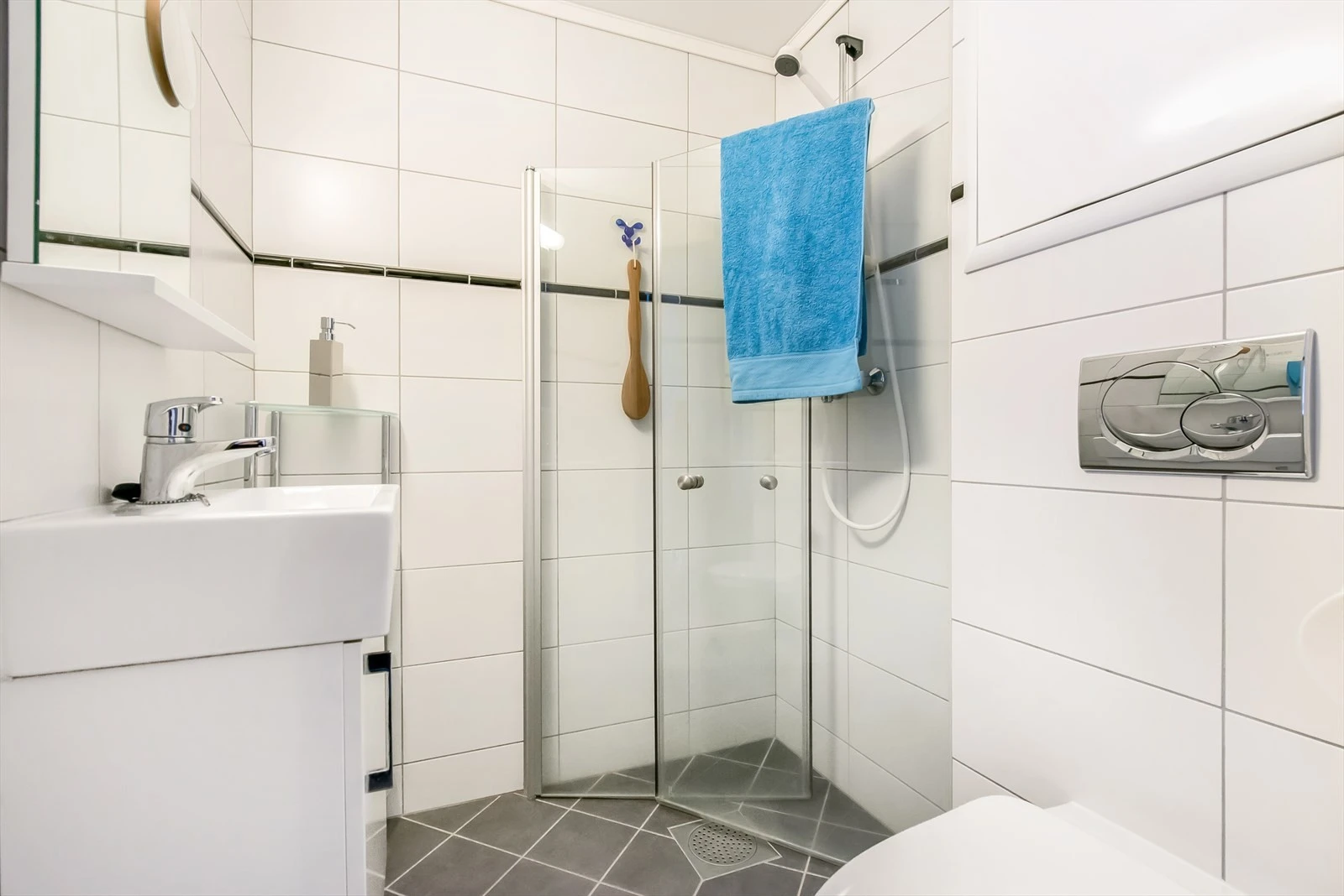 Innredning består av vegghengt wc, innfellbare dusjdører i glass, servant med møblement og speil. Galleribilde