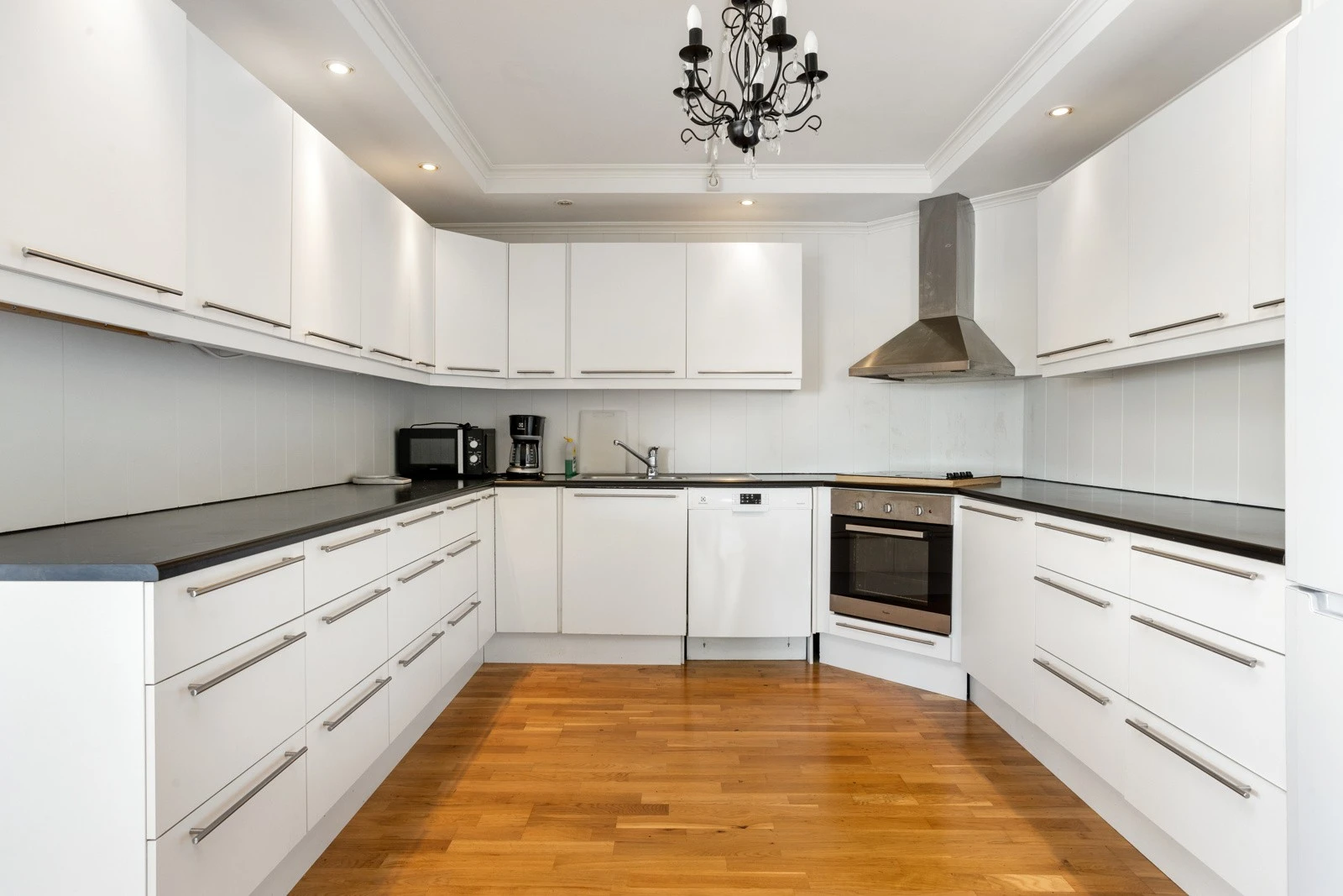 Kjøkken med pen hvit slett innredning med moderne delvis åpen løsning mot stuen Galleribilde