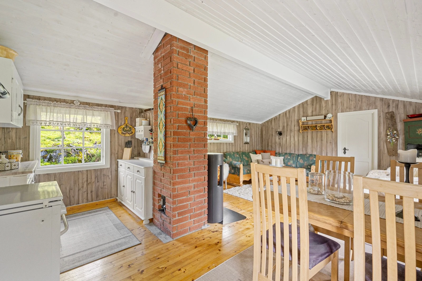 Stue og kjøkken i åpen løsning med plass til spisebord, sofa og andre sittemøbler. Galleribilde