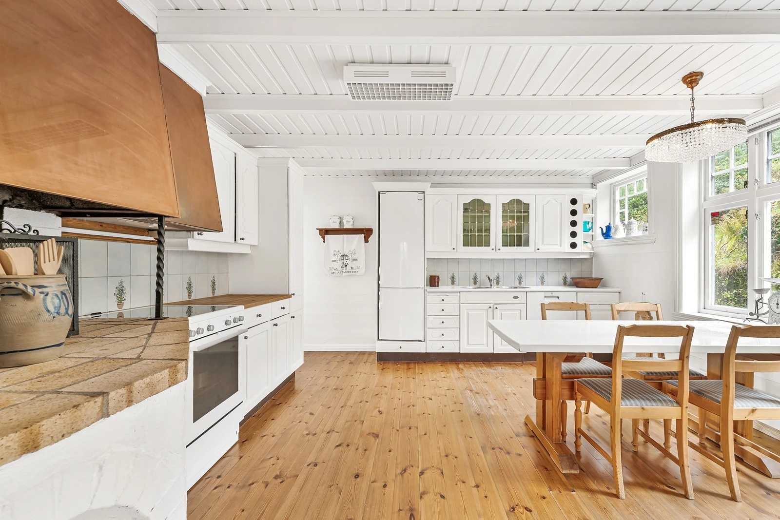 Kjøkkeninnredning med hvite profilerte fronter og laminat benkeplate. Galleribilde