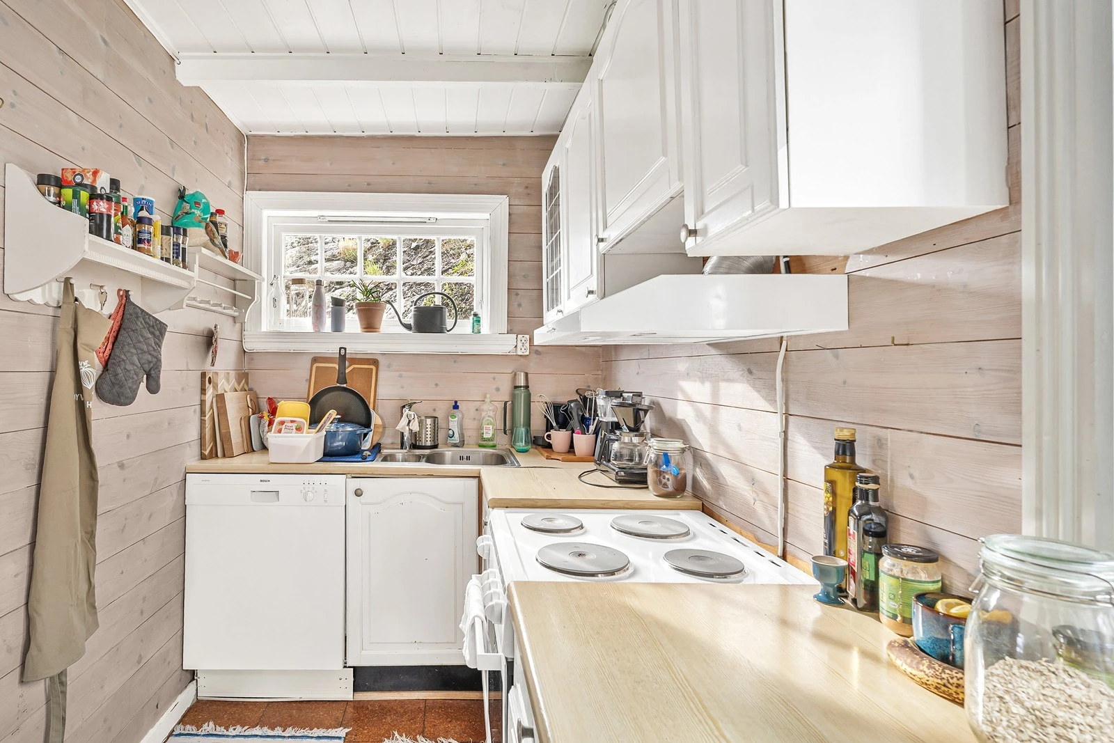 Kjøkken i anneks med malt profilert kjøkkeninnredning med laminat benkeplate. Frittstående oppvaskmaskin, komfyr og kjøleskap. Galleribilde