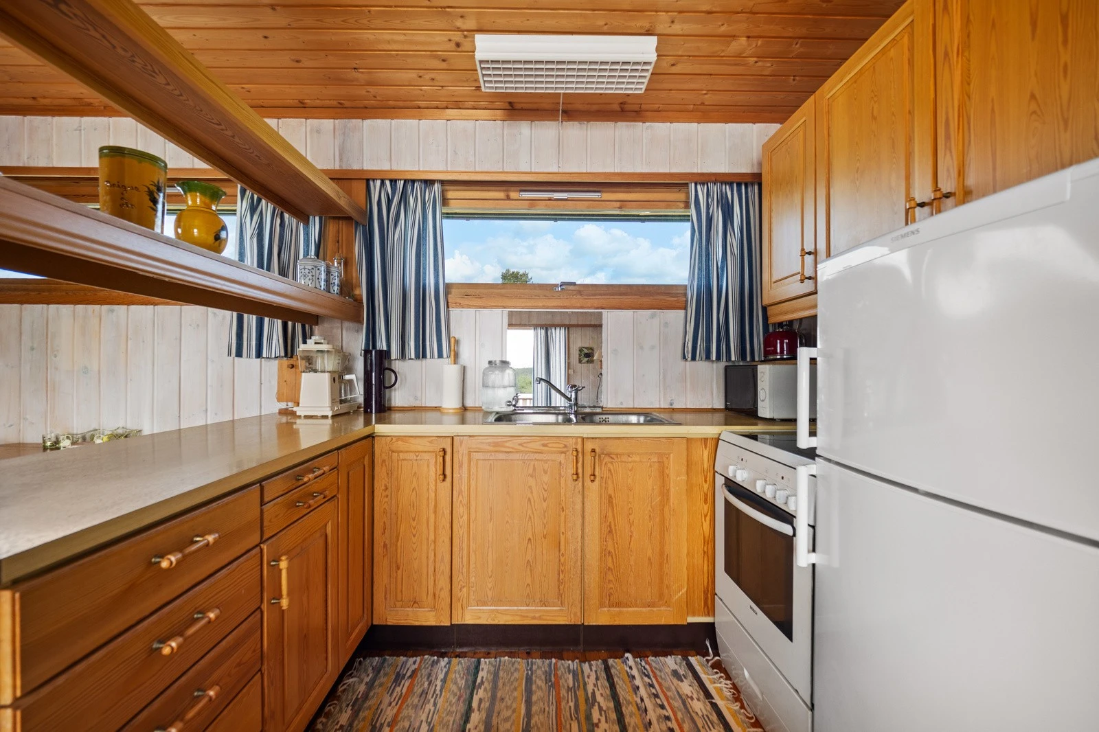 Kjøkkenet er oppført i en smart u-form, med åpne hyller, fin skapplass og en barløsning som samlingspunkt. Galleribilde