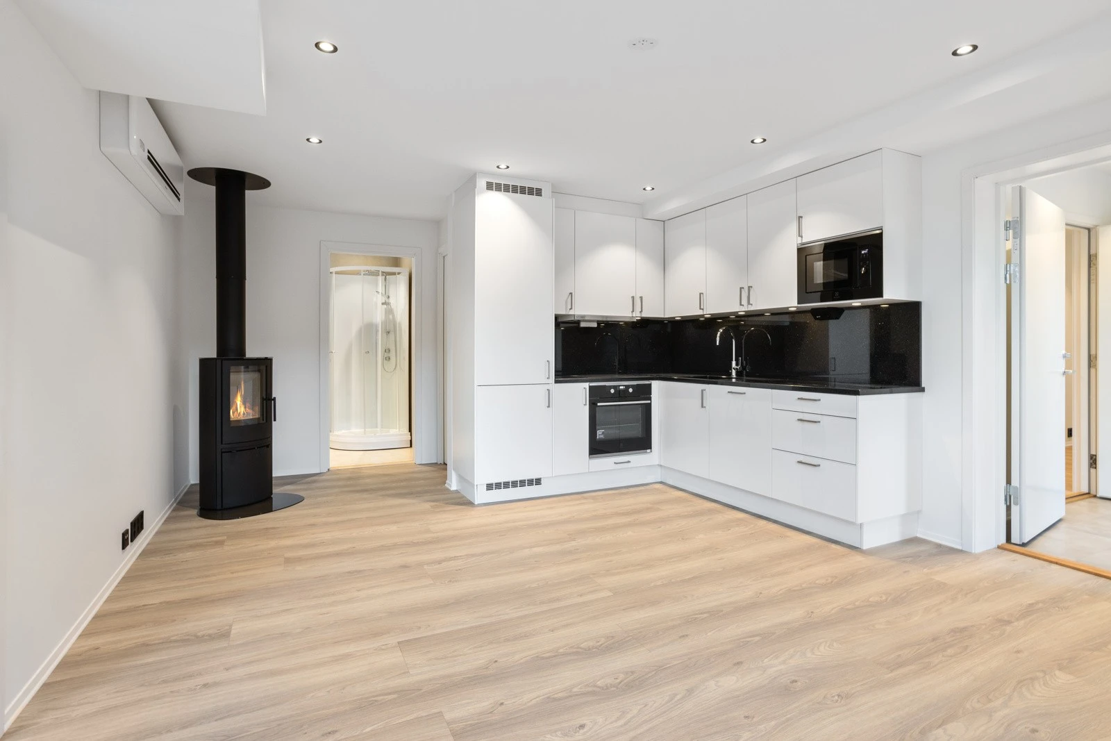 Stue med åpen moderne løsning | Uno Snø innredning med integrerte hvitevarer | benkeplate i granitt "Black Galaxy" Galleribilde