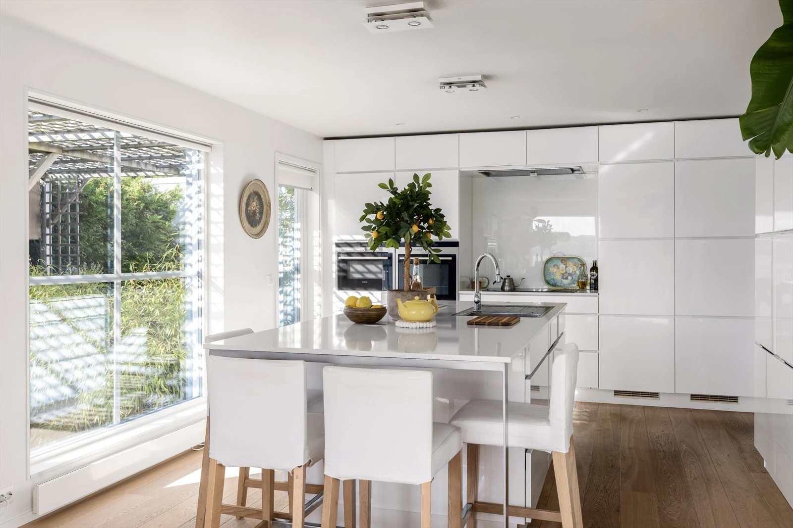 Kjøkkenet er av høy kvalitet og har en delikat og tidløs stil. Løsningene er funksjonelle og gjennomtenkte. Det samme gjelder for belysningen. Fra kjøkkenet er det direkte utgang til terrassen med pergola. Galleribilde