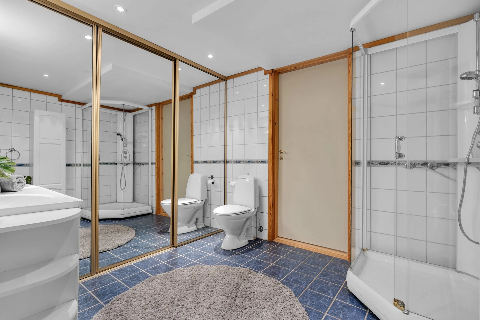 Stort, flislagt bad med skyvedører til utslagsvask og vaskemaskin. Galleribilde