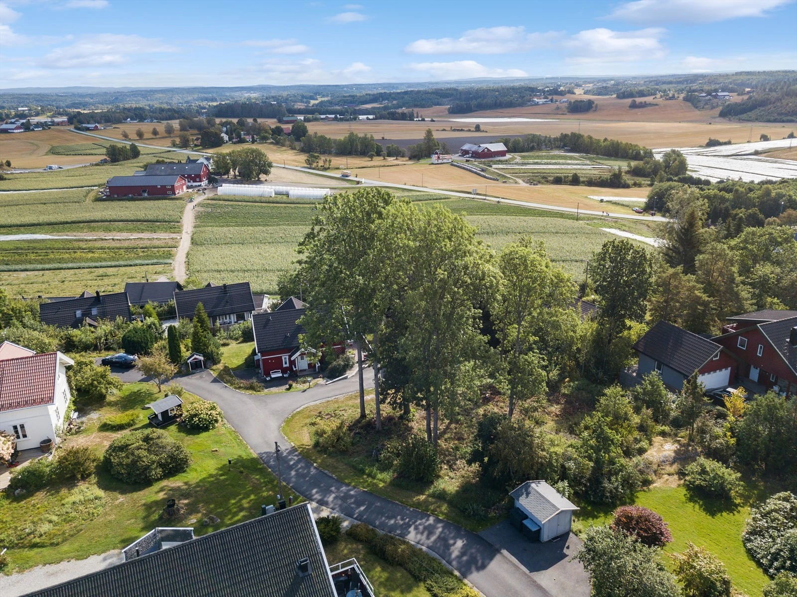 Det er klartgjort asfaltert vei, vann, avløp, strøm og fiber til tomten. Det er felt noen trær siden dette bilde ble tatt. Galleribilde