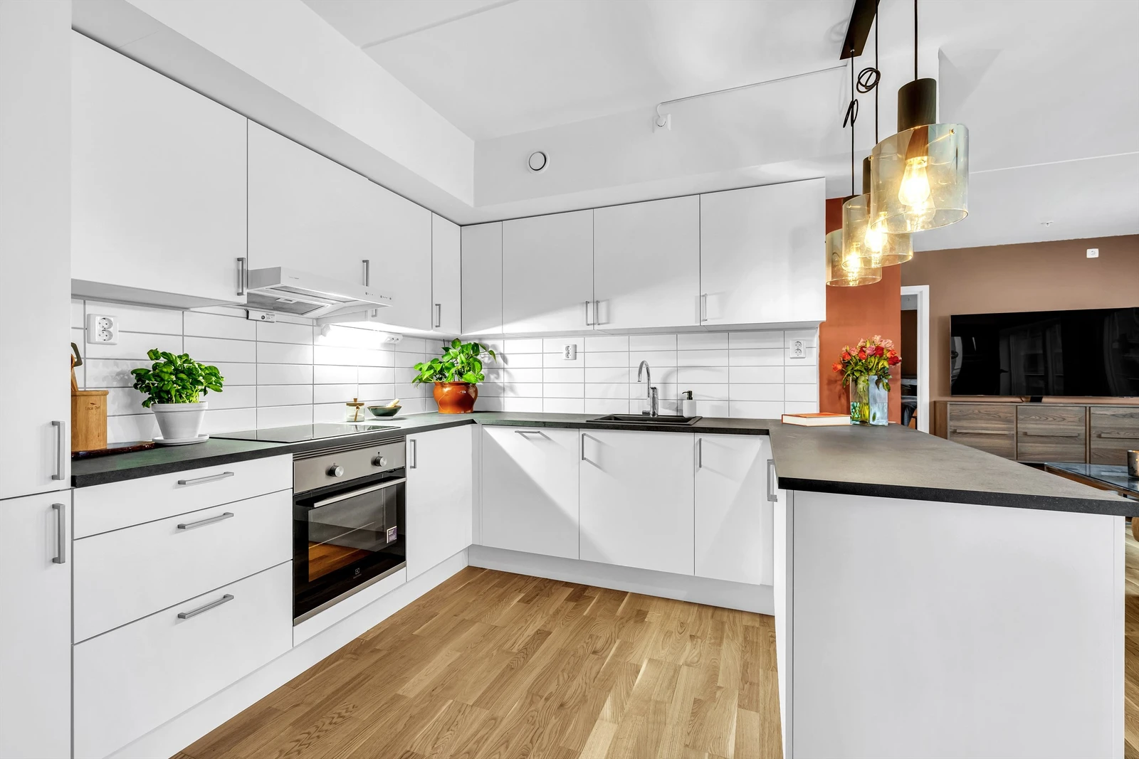 Kjøkkeninnredning med slette fronter fra HTH, belysning under overskap og integrerte hvitevarer Galleribilde