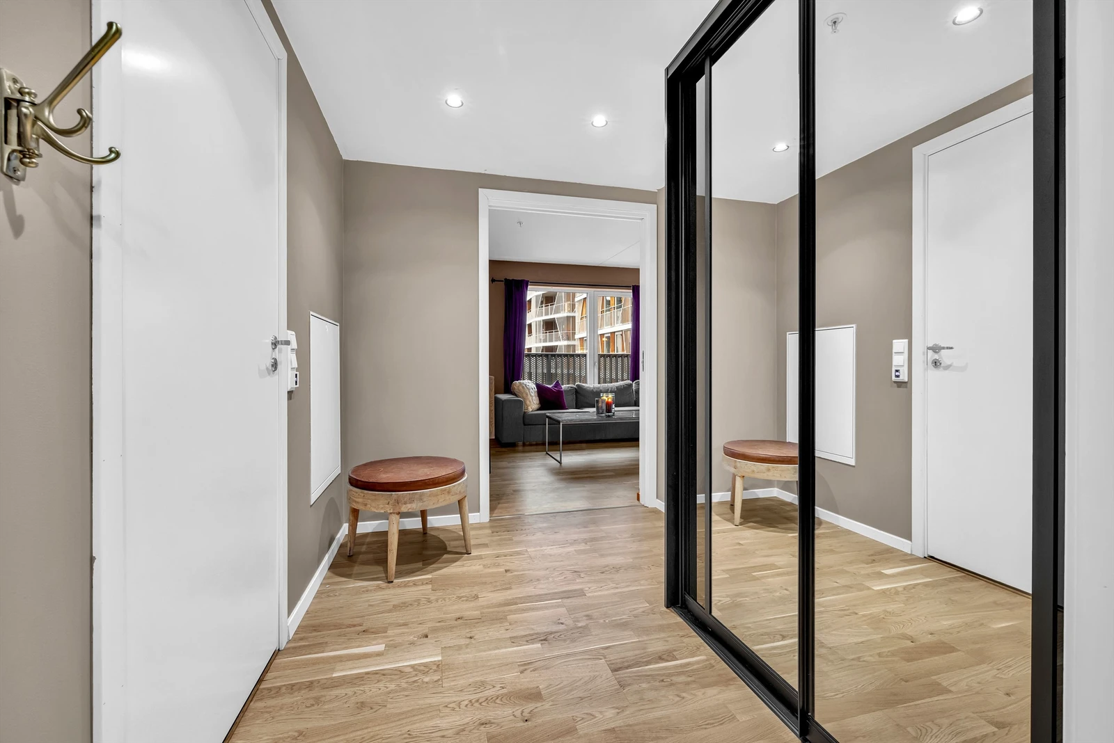 Romslig entrè med skyvedrøsgarderobe, klesopphenging og tilkomst til boligens innvendige bod Galleribilde