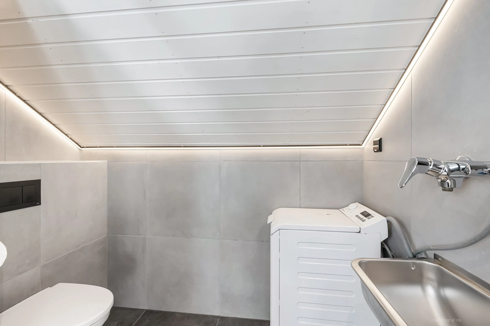 Moderne baderomsinnredning med opplegg for vaskemaskin.