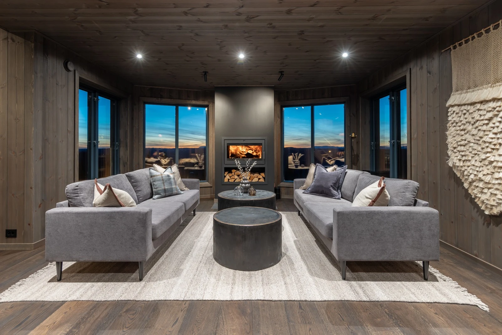 Velkommen inn! En av hyttas to stuer med store vinduer, peisinnsats og ferdig møblert sofagruppe Galleribilde