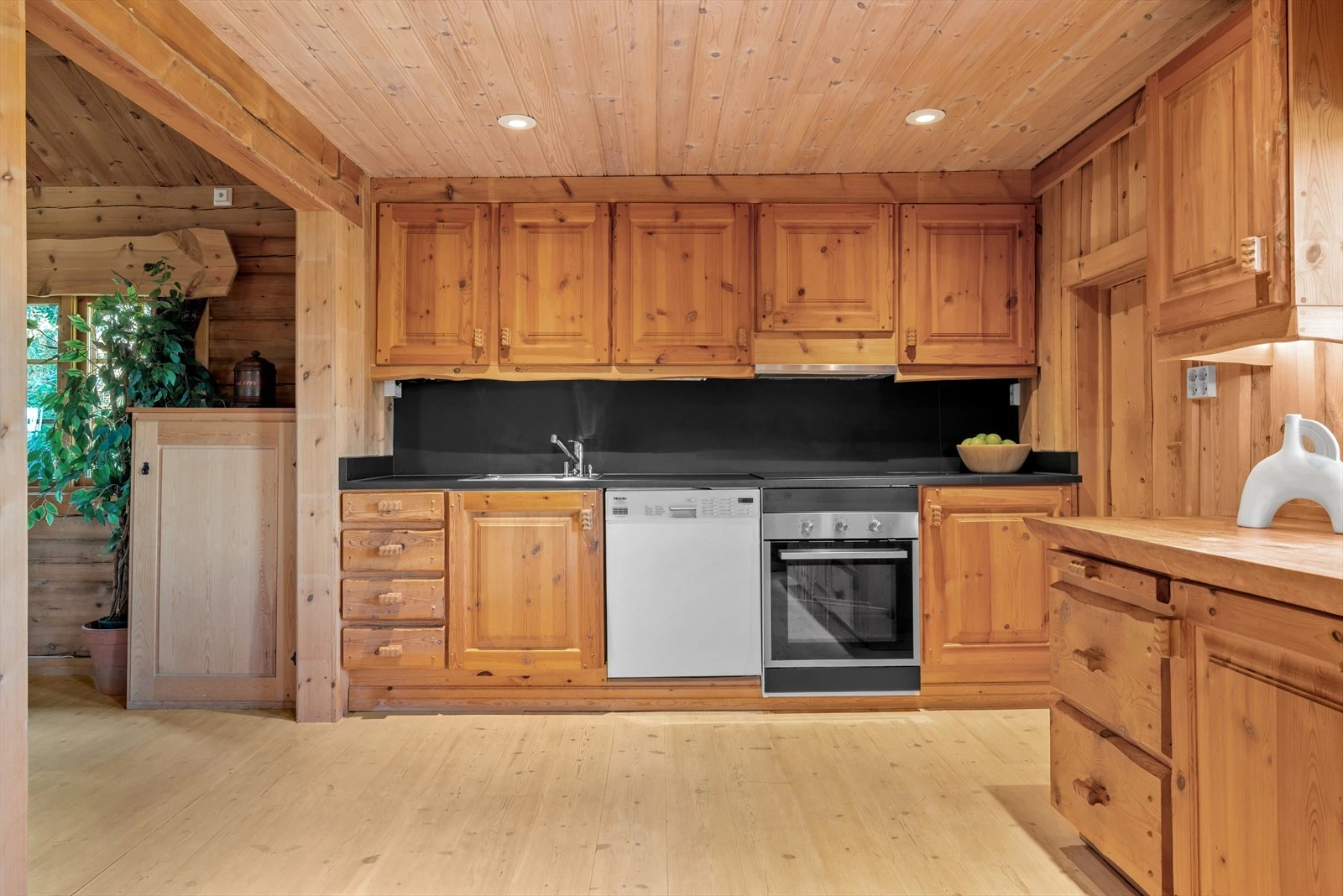 Kjøkkenet er lunt og romslig, med enstavs furugulv, laftede tømmervegger og egen matbod for ekstra oppbevaring. Galleribilde