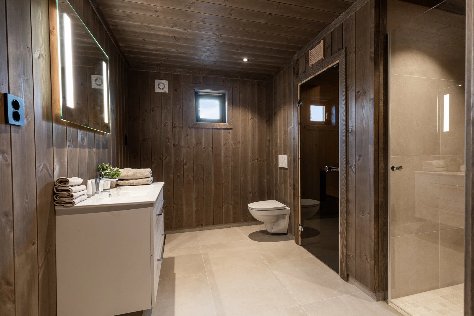 Dette badet har en imponerende størrelse og er innredet med veggehengt toalett, dusj og baderomsinnredning. Galleribilde