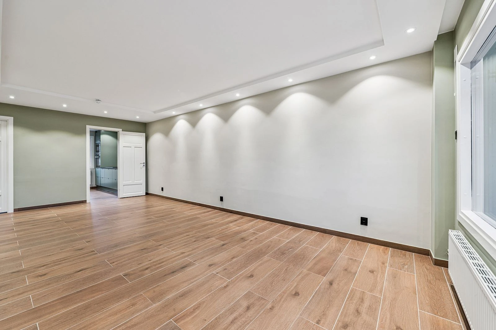 En stue som innbyr til både hverdagshygge og selskap - med mange spotlights i taket som skaper en lun og moderne atmosfære.