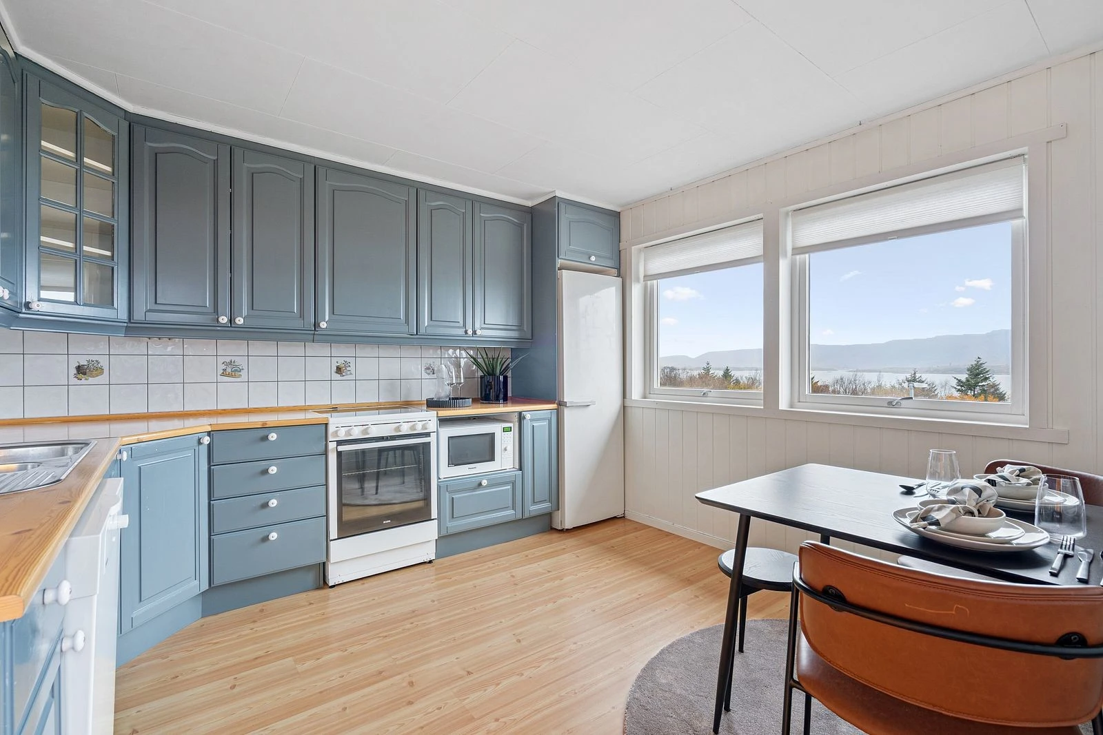 Praktisk kjøkken med frittstående hvitevarer og plass til spisegruppe Galleribilde