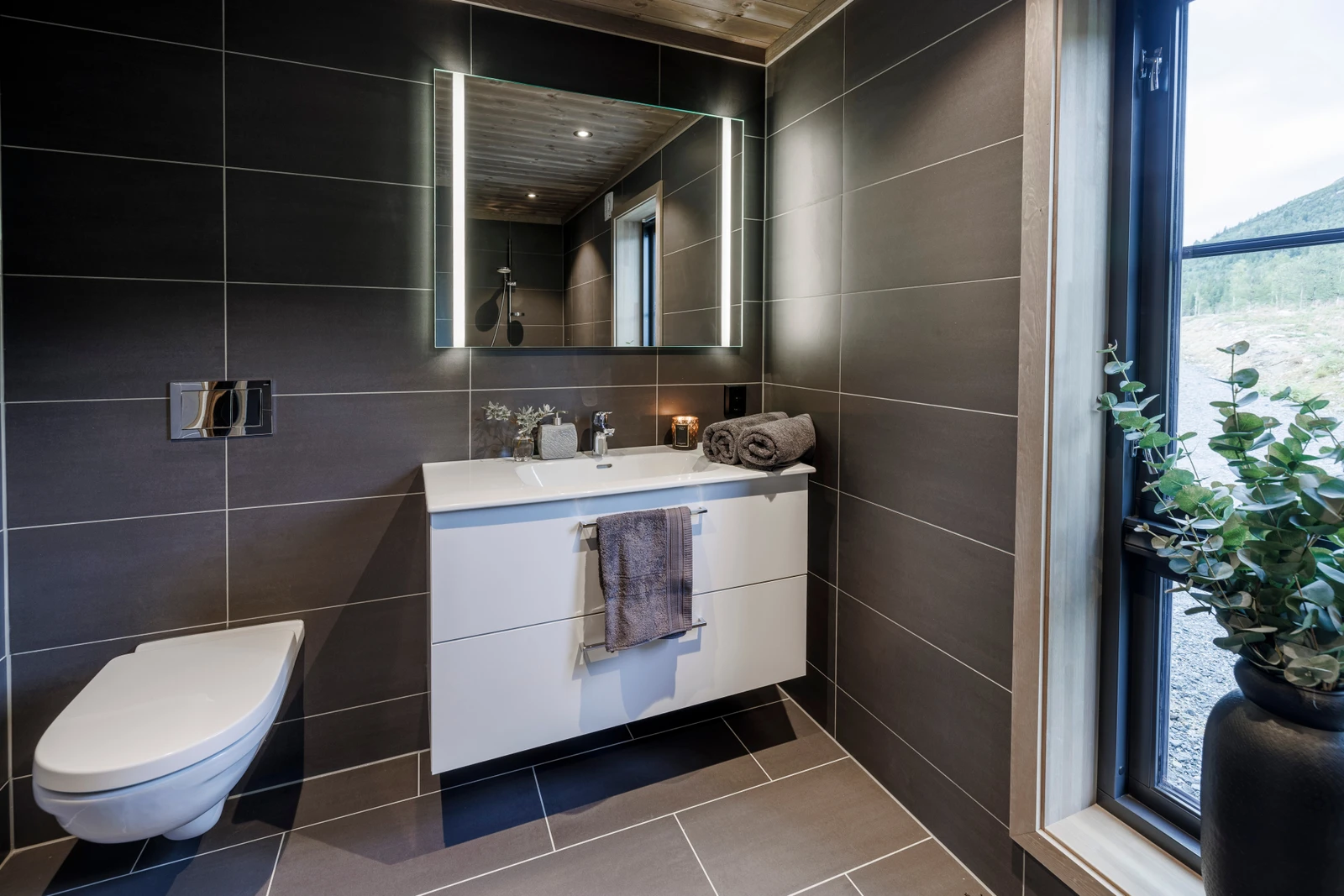 Et delikat og flislagt baderom med blant annet gulvvarme og dusjnisje Galleribilde