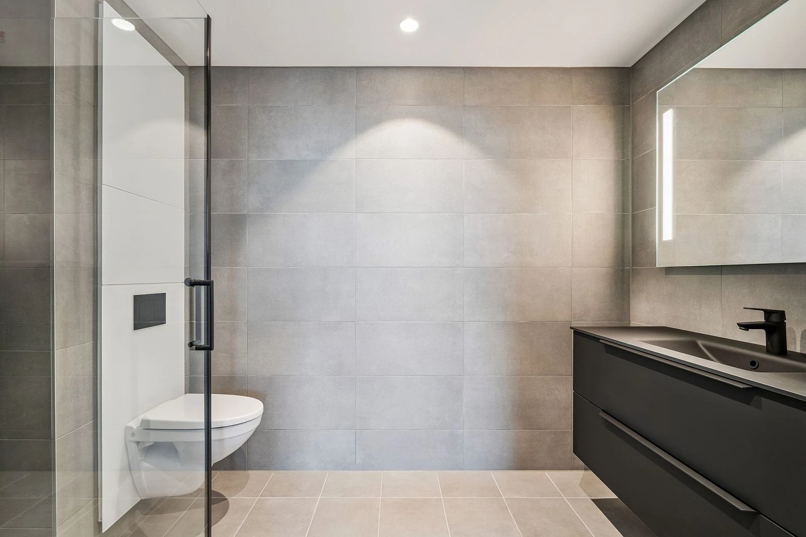 Vegghengt toalett og elegant servant med speil og belysning.