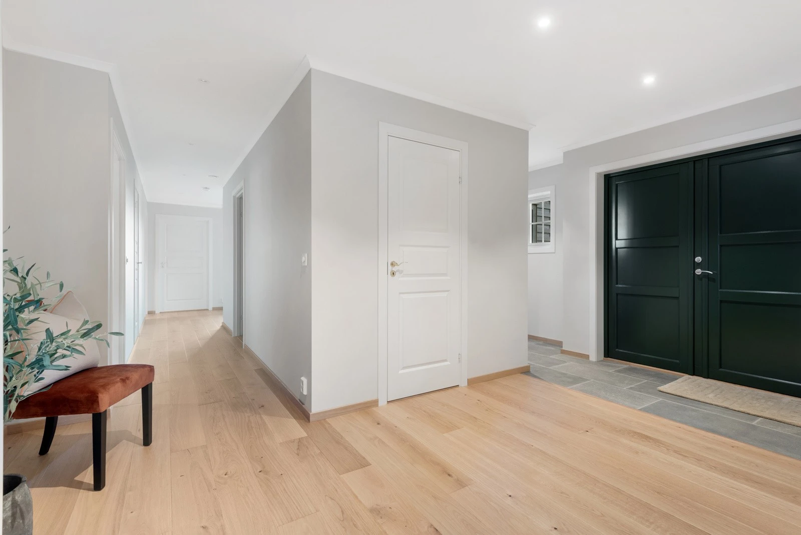 Du kommer i en romslig entré med fliser på gulvet og adkomst til garderobe og gjestetoalett Galleribilde