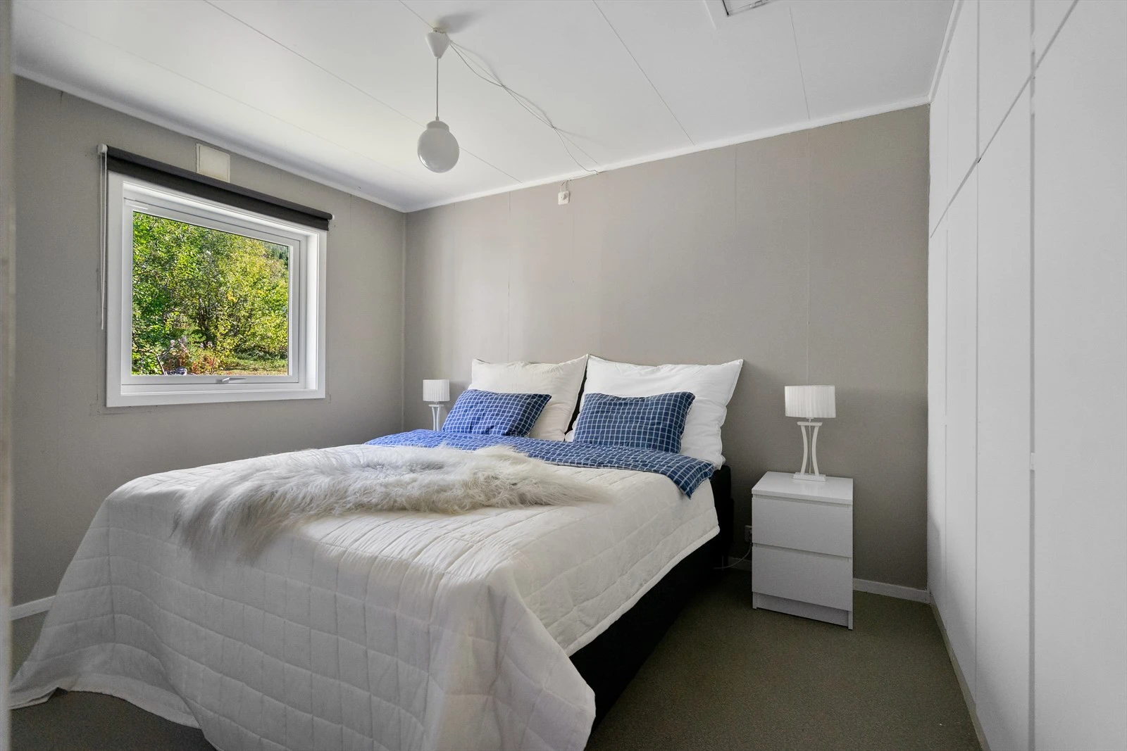 Soverom med lyse vegger og stort vindu som slipper inn rikelig med dagslys Galleribilde