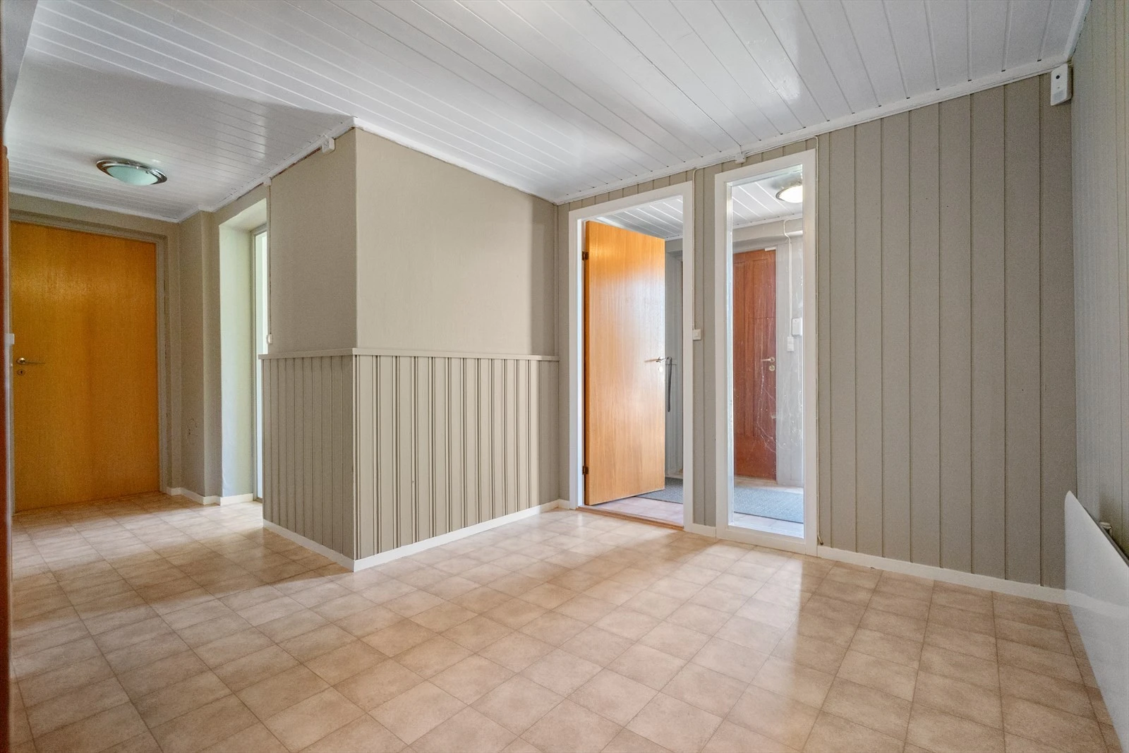 Romslig hall med praktiske flater og trapp opp til hovedetasjen Galleribilde