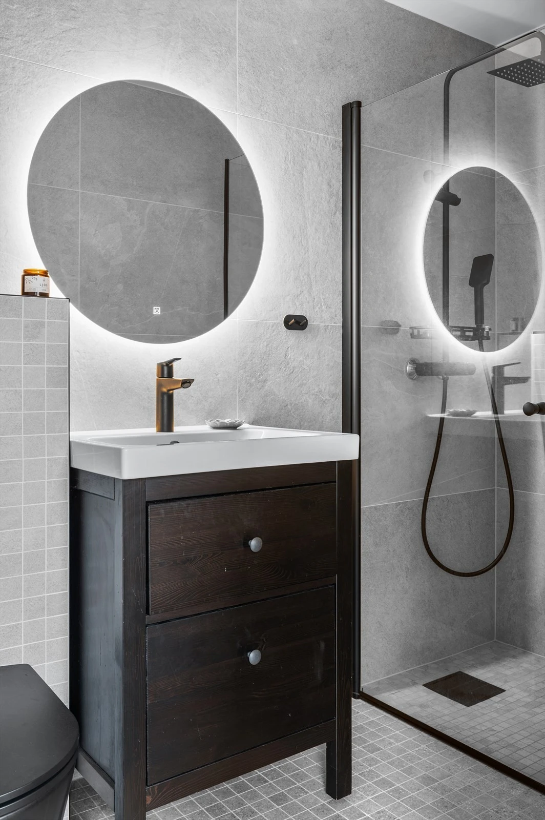 Badet gir umiddelbart en gode spafølelsen med store og små fliser, stor dusjnisje, vegghengt wc, svart armatur og baderomsmøbler. Galleribilde