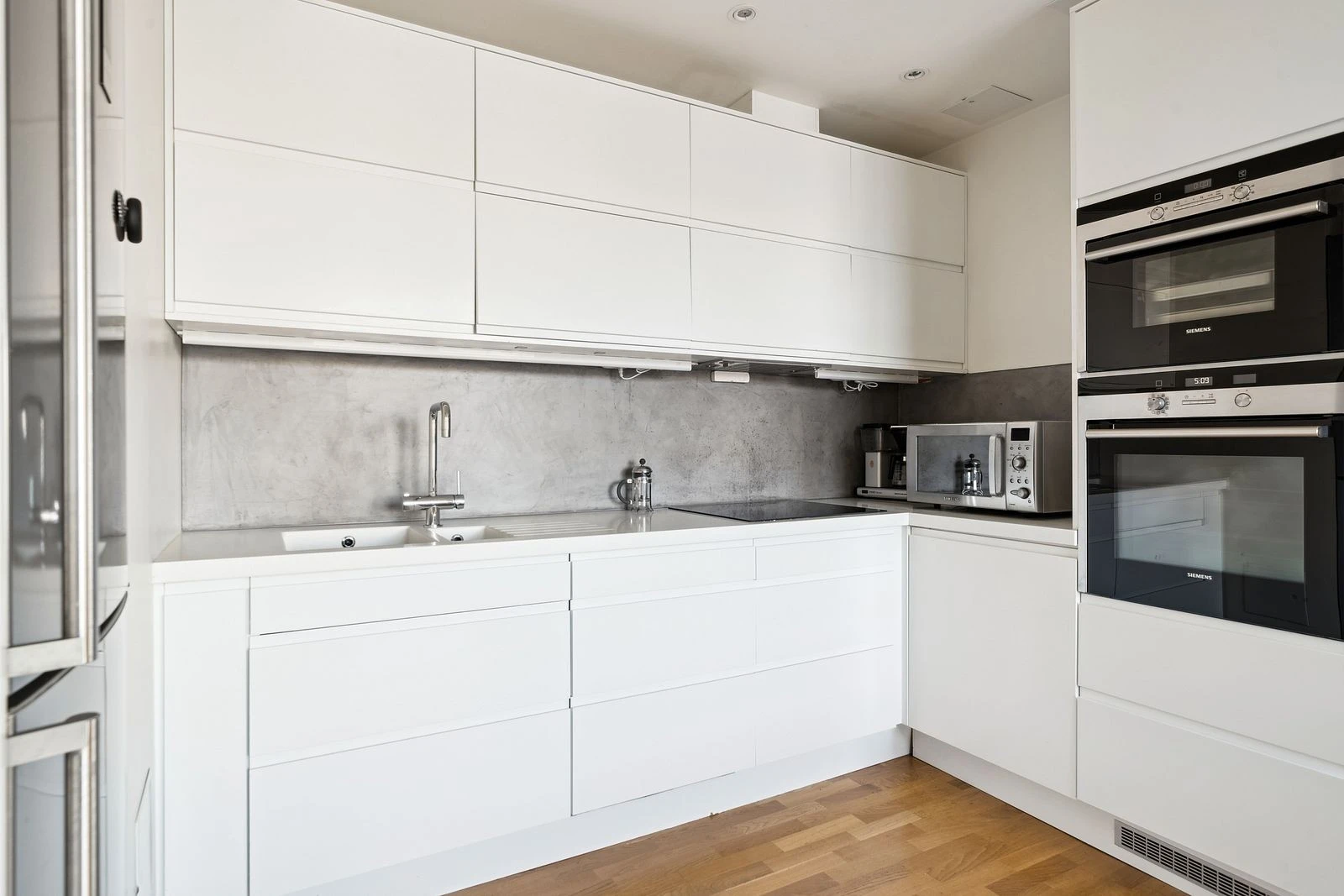 Morderne kjøkken med integrerte hvitevarer og stålfarget frittstående kombiskap og micro. Galleribilde