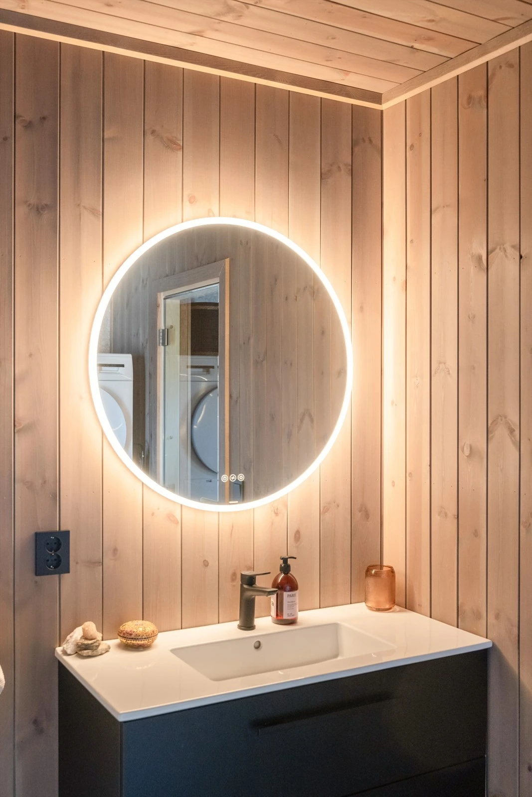 Servantinnredning med underskuffer og speil. Det er opplegg for vaskemaskin, og elektrisk vifte på vegg. Galleribilde