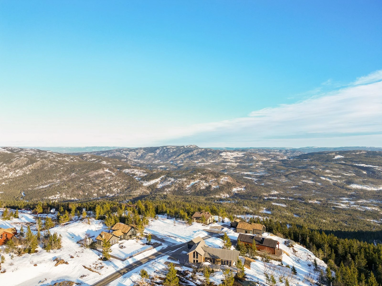 Det er vei helt fram og gruset parkeringsplasser rett utenfor hytta. Det er montert elbil lader på husvegg. Galleribilde