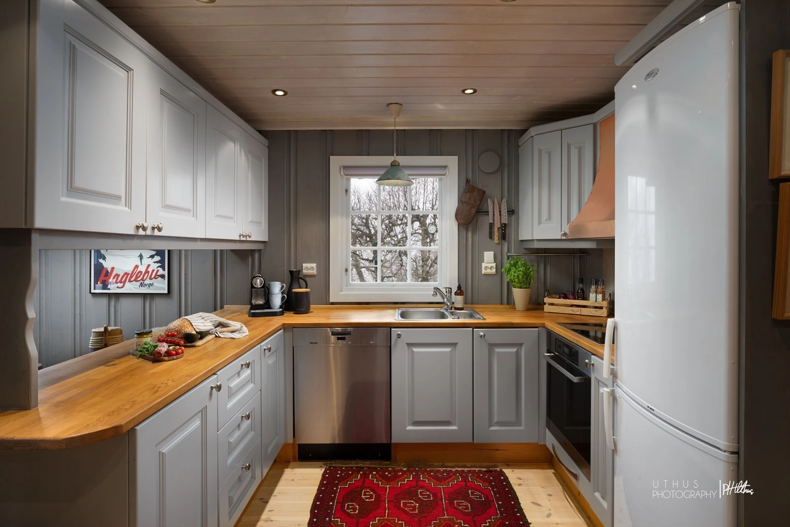 Profilerte kjøkkenfronter og benkeflate i heltre. Integrert induksjonstopp og stekeovn. Opplegg til oppvaskmaskin. Galleribilde