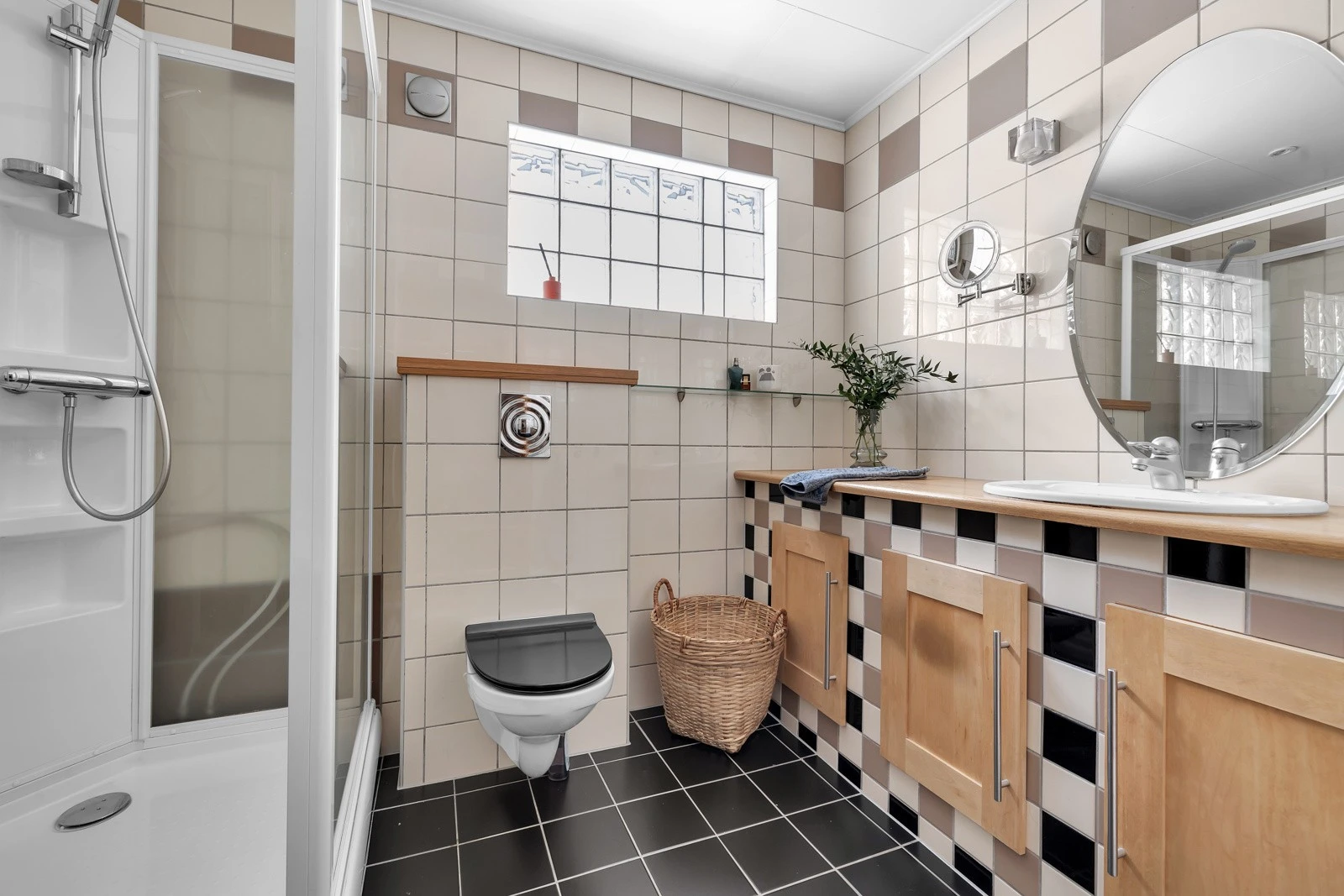 Flislagt bad med dusjkabinett og veggopphengt wc. Galleribilde