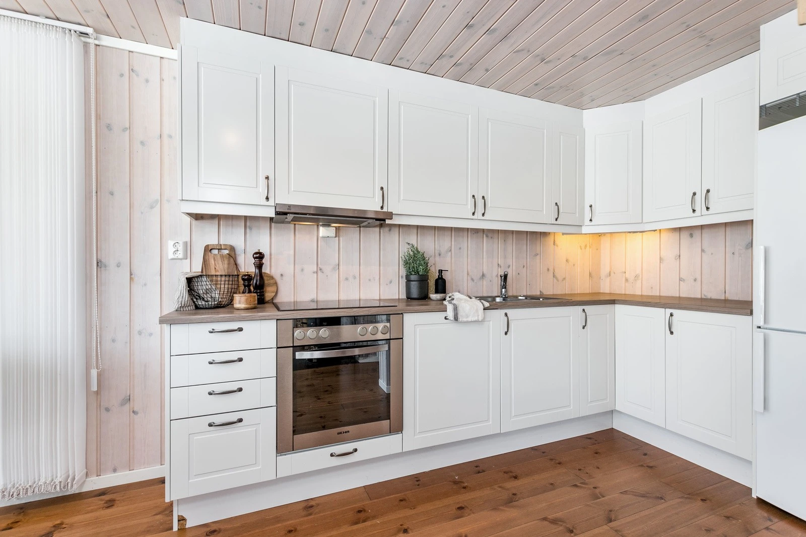 Innredningen består av hvite profilerte fronter og benkeplate i laminat med nedfelt vaskekum i rustfritt stål. Stekeovn, keramisk topp og oppvaskmaskin er integrert i innredningen. Galleribilde