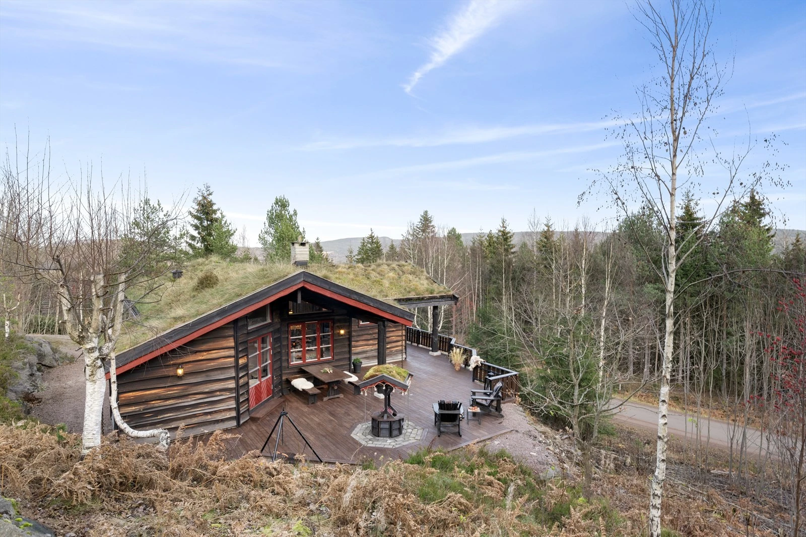 Hytta ligger fint til i skrående terreng, omgitt av naturlig vegetasjon. Galleribilde